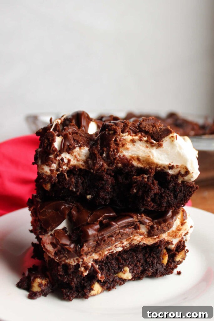 Stack of layered rocky road style brownies on plate.