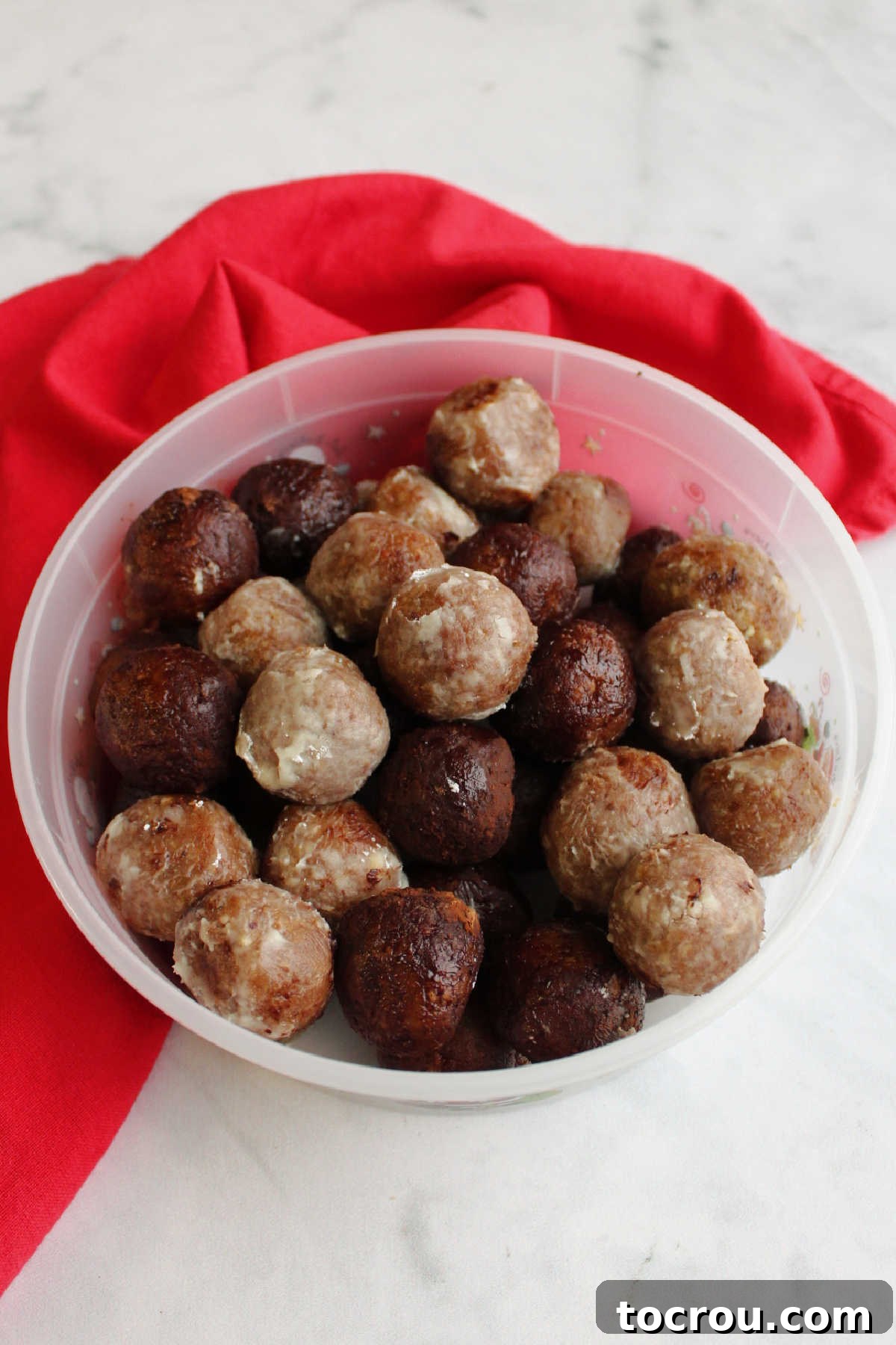 Kentucky Bourbon Pecan Truffles 9 Clear plastic storage container filled with neatly arranged pecan bourbon balls, some coated in powdered sugar, ready for chilling or serving at a party.
