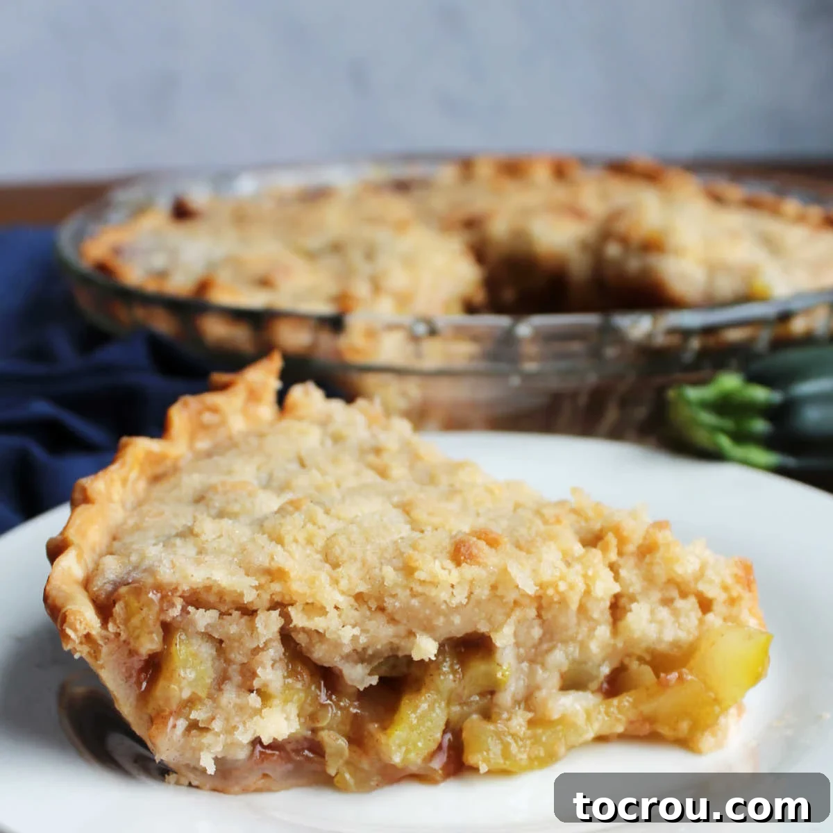 Close-up of a perfectly baked slice of mock apple zucchini pie, revealing the spiced filling and golden, buttery crumb topping.