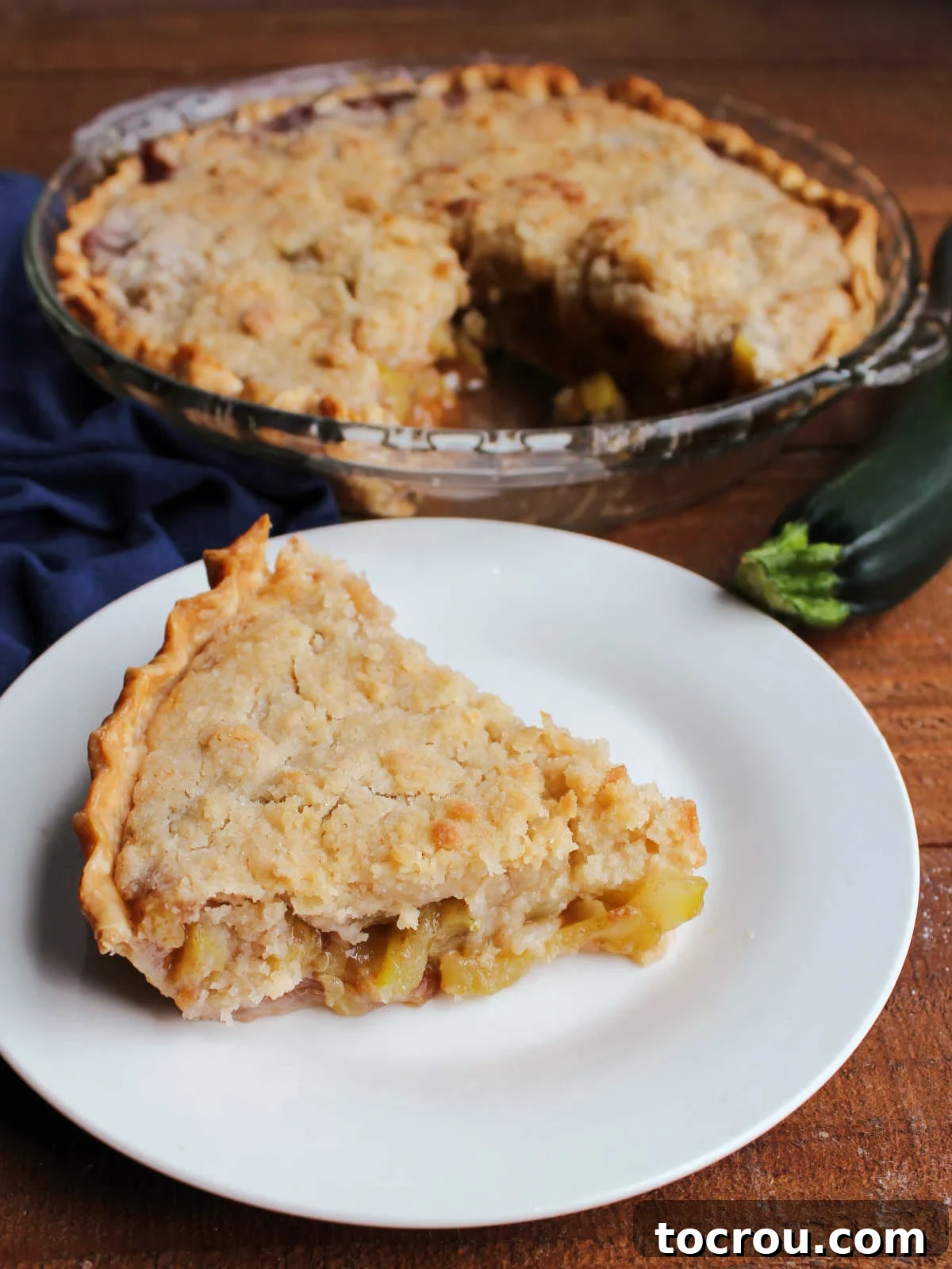 A mouthwatering slice of zucchini pie, generously topped with a rich, buttery crumb, rests on a plate, ready to be enjoyed as a delightful dessert.