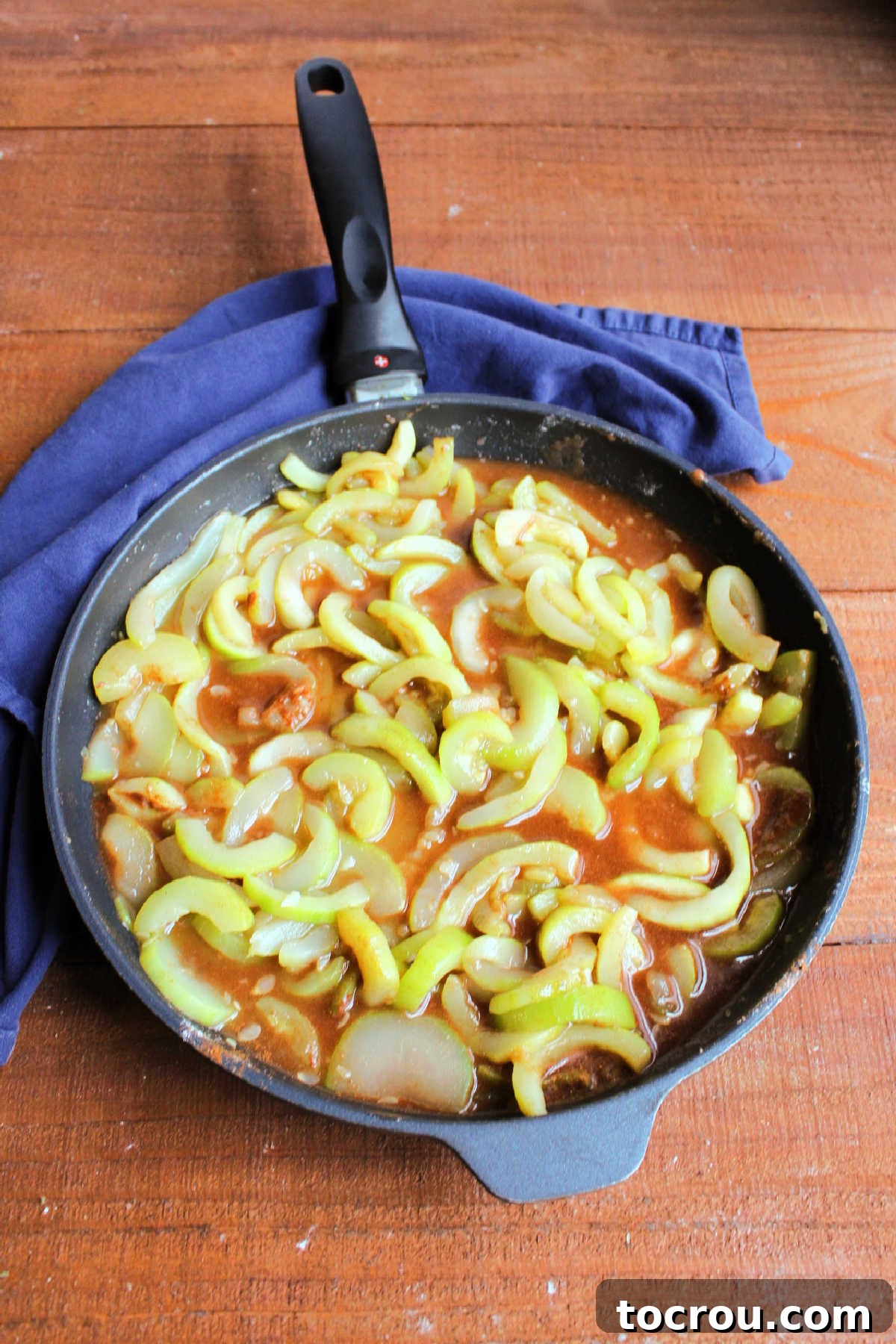 The perfectly seasoned zucchini and cinnamon mixture, shimmering in a skillet, is poised to be poured into the awaiting pie crust.