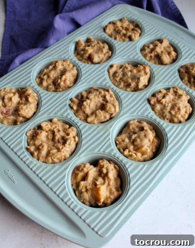 Muffin tin with wells filled with peach muffin batter, ready for baking.