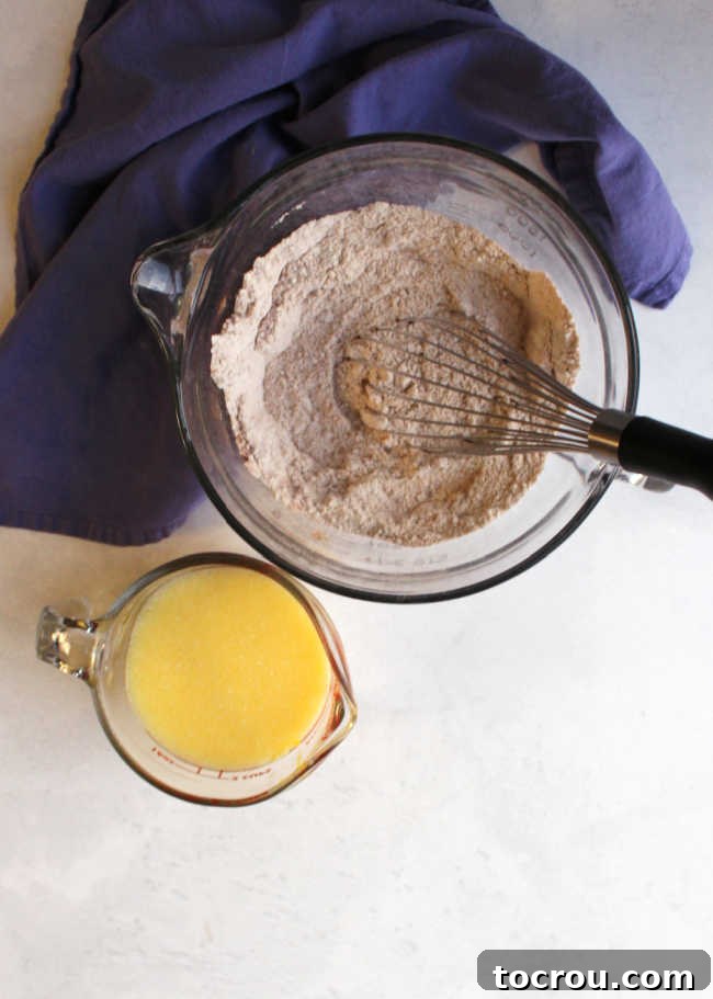 Muffin Ingredients Preparation Batter bowl with dry ingredients for muffin inside next to measuring cup with wet ingredients.