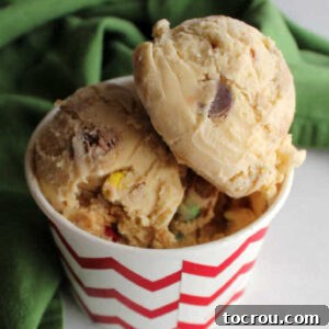 Scoops of monster cookie dough ice cream with peanut butter, oatmeal, and colorful candies visible inside, ready to be enjoyed.