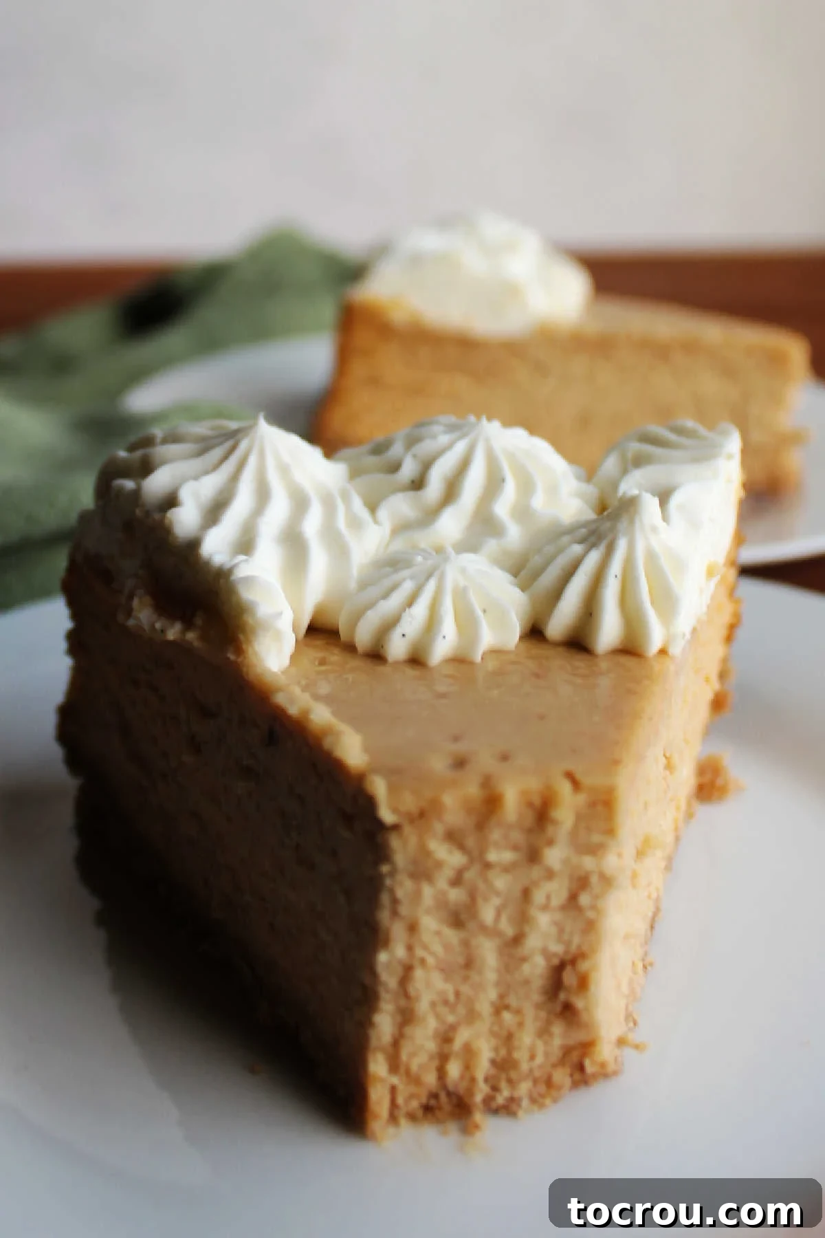 A fork taking a bite out of a creamy slice of apple butter cheesecake, highlighting its smooth texture and delightful golden hue.
