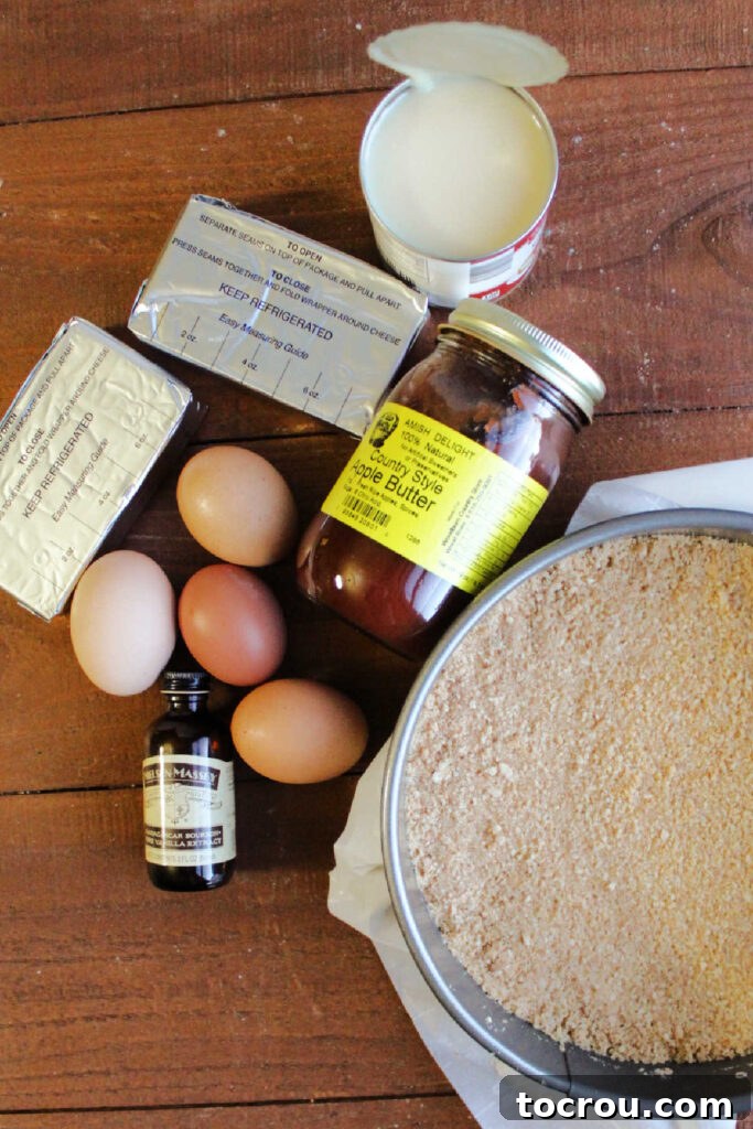 A neatly arranged collection of ingredients, including cream cheese, sweetened condensed milk, eggs, vanilla extract, and apple butter, ready for making cheesecake.