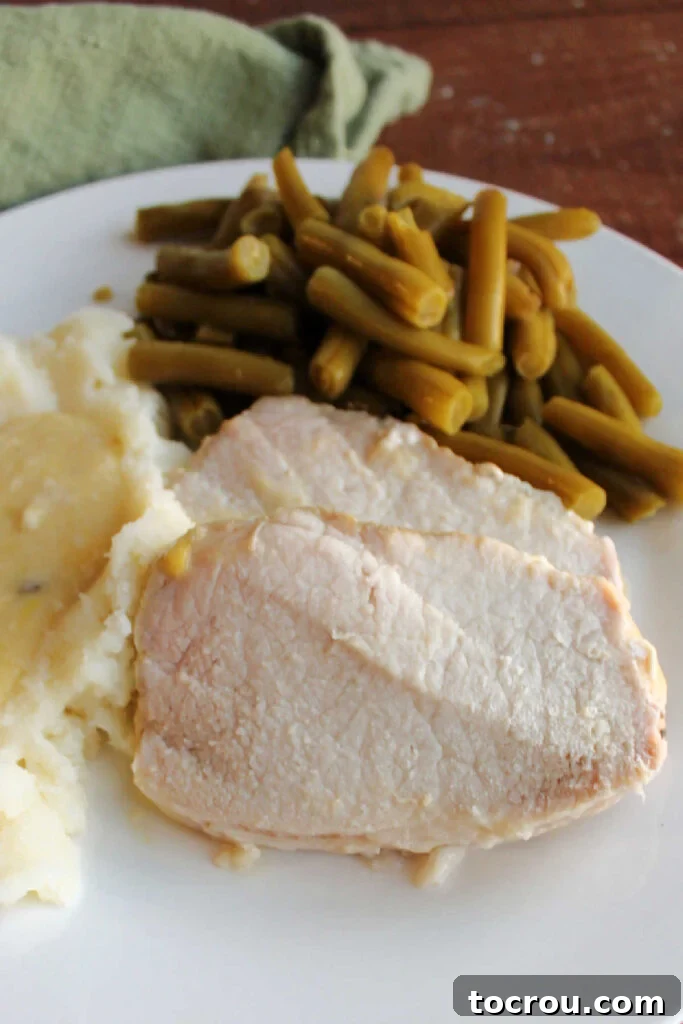 Fork Tender Pork Loin with Velvety Gravy 7 Close up of sliced pork loin on dinner plate.