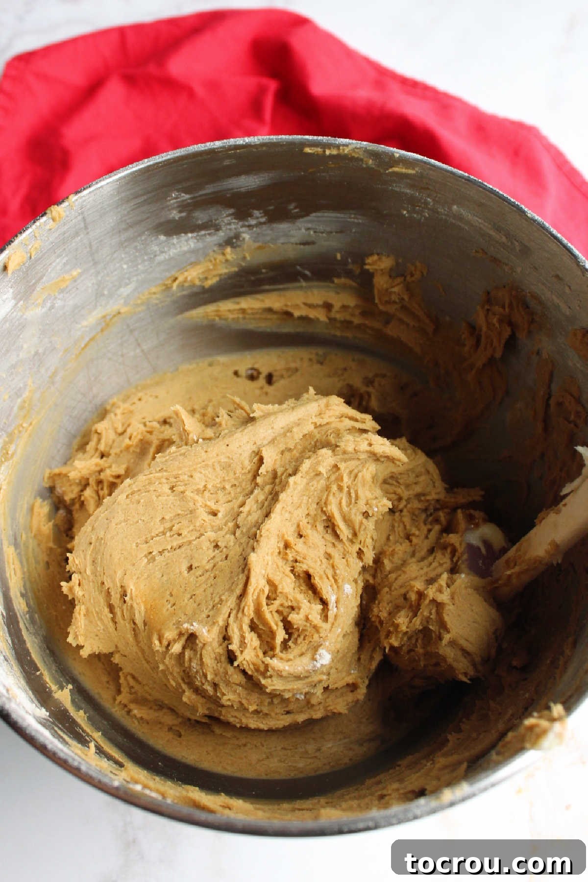 A mixing bowl filled with rich, brown gingerbread cookie dough, ready for baking.