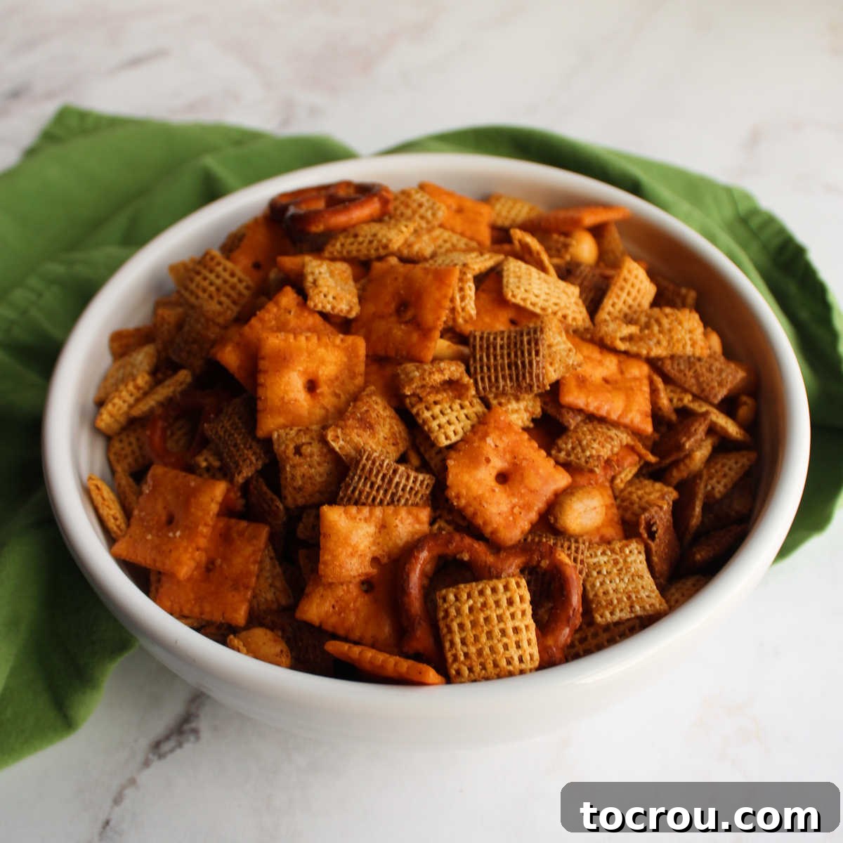 Bowl of taco chex mix with cheese crackers, pretzels, peanuts and cereal ready to eat.