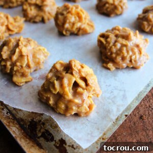 Mounds of perfectly formed peanut butter honey cornflake cookies arranged on wax paper, glistening and ready to be enjoyed.
