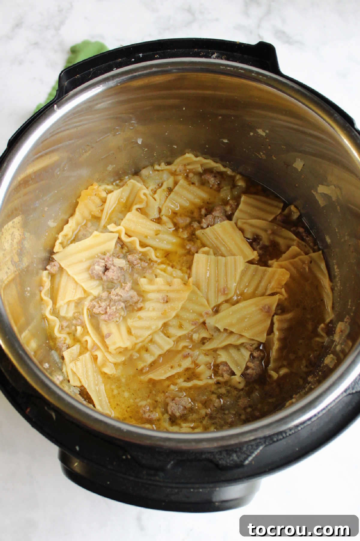 Cooked pasta with chicken broth and sausage in Instant Pot.
