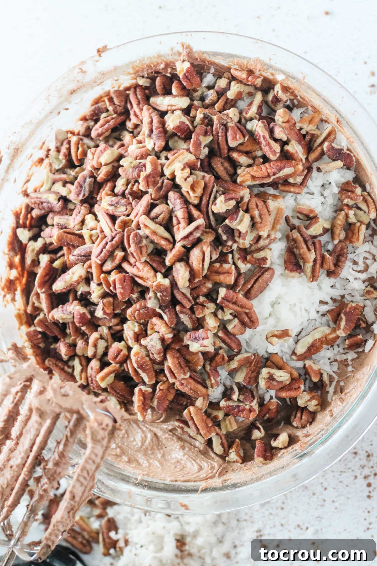 Mixing chopped pecans and coconut into chocolate cake batter.