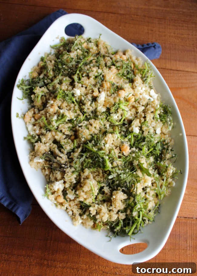 Large serving bowl filled with Mizuna Greens and Quinoa Salad, featuring vibrant greens, crumbled feta, and chickpeas, ready to be enjoyed.