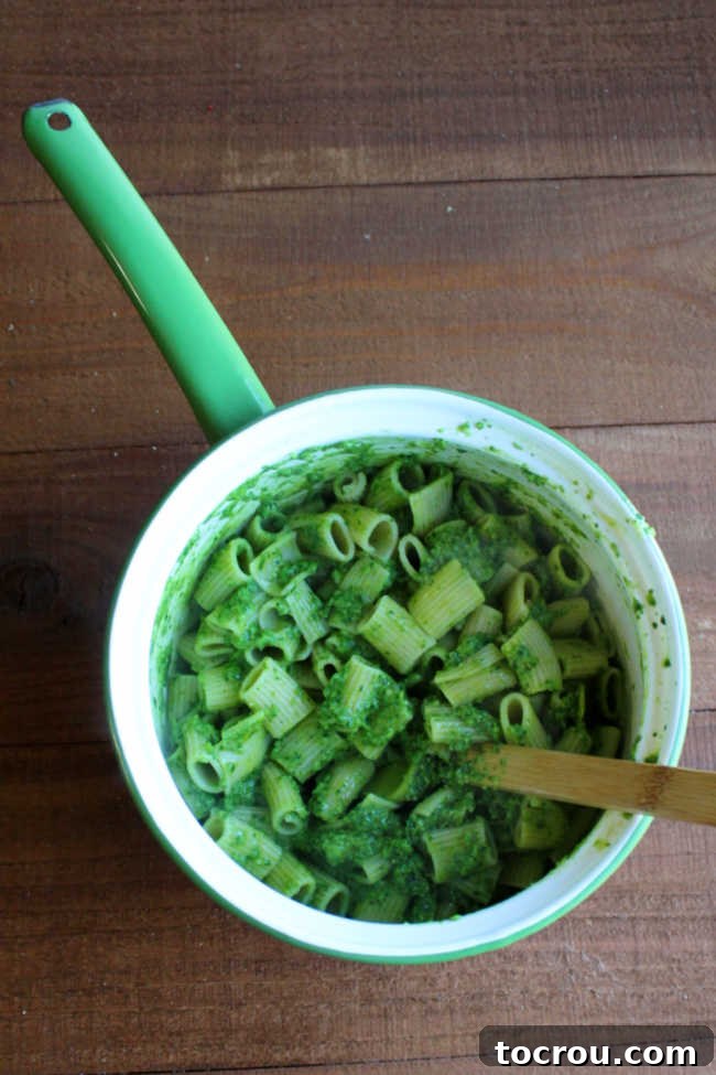 Vintage enameled saucepan filled with pasta tossed in garlic scape and spinach mixture.