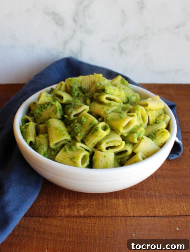Bowl of pasta coated in luscious spinach and garlic scape pesto, ready to be served.