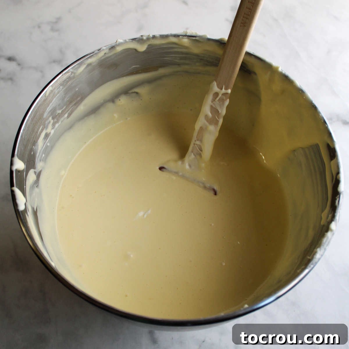 Mixing bowl filled with creamy sweetened condensed milk cheesecake mixture.