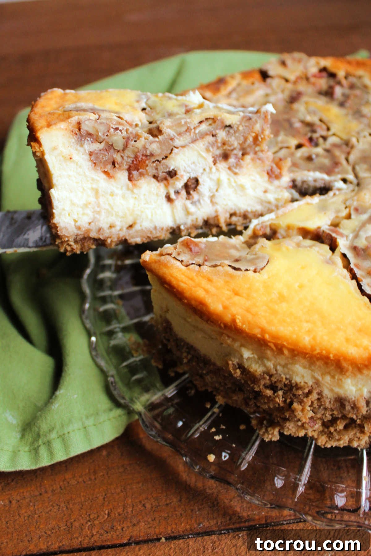Lifting slice of pecan pie cheesecake out of whole pie.