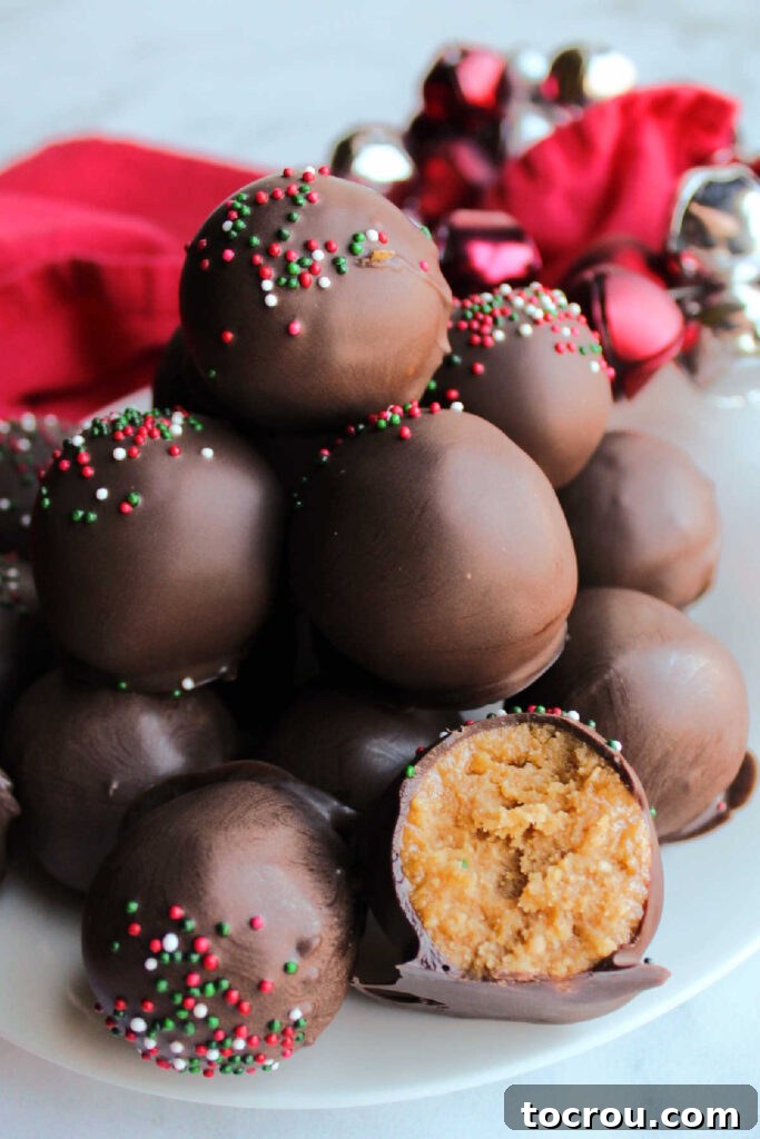 Pile of peanut butter truffles with one cut open to show the creamy peanut butter center.