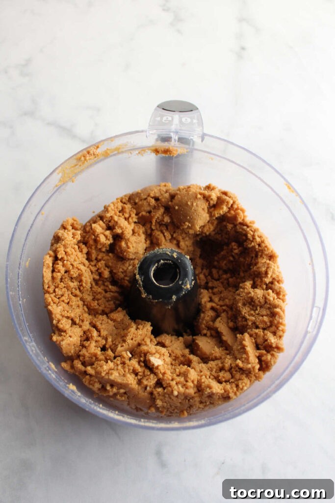 Smooth, dough-like peanut butter cookie truffle mixture in a food processor, indicating it's ready for shaping.