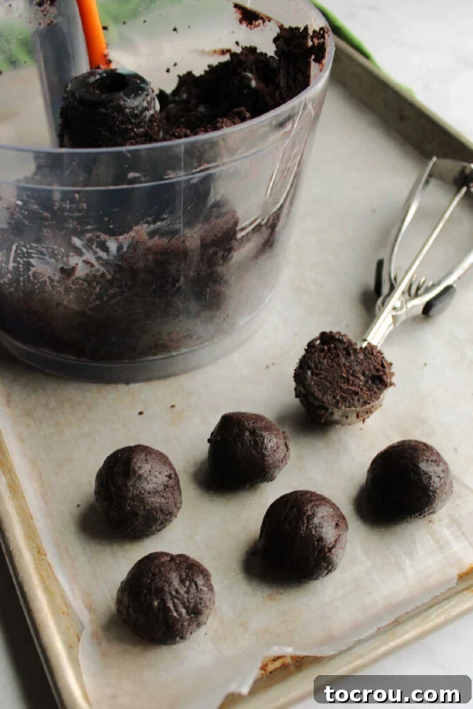 Creamy No-Bake Oreo Truffles 5 Scooping out condensed milk Oreo mixture and rolling it into balls.