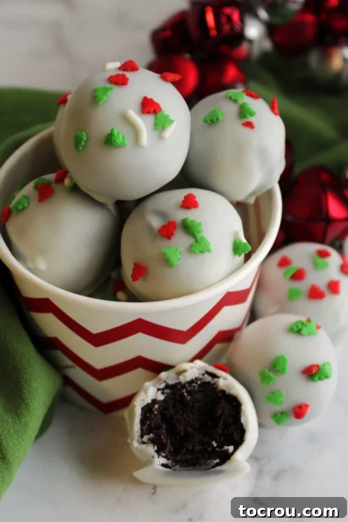 Creamy No-Bake Oreo Truffles 8 Red and white bowl filled with condensed milk Oreo truffles with one missing a bite in the front showing the dark chocolate center.