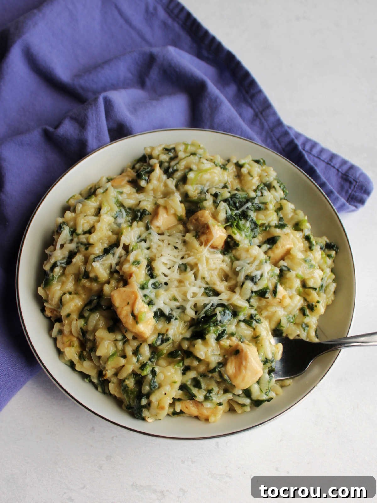fork going in for first bite of creamy chicken and spinach risotto.