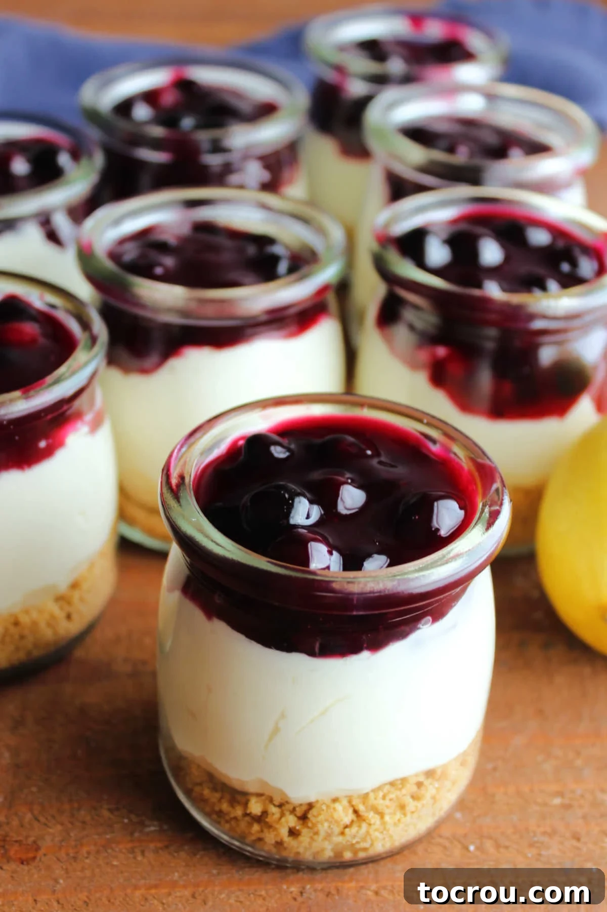 Quick Lemon Berry Jar Cheesecakes 13 Pudding jars filled with graham cracker crust, no bake lemon cheesecake filling, and homemade blueberry sauce, ready to eat.