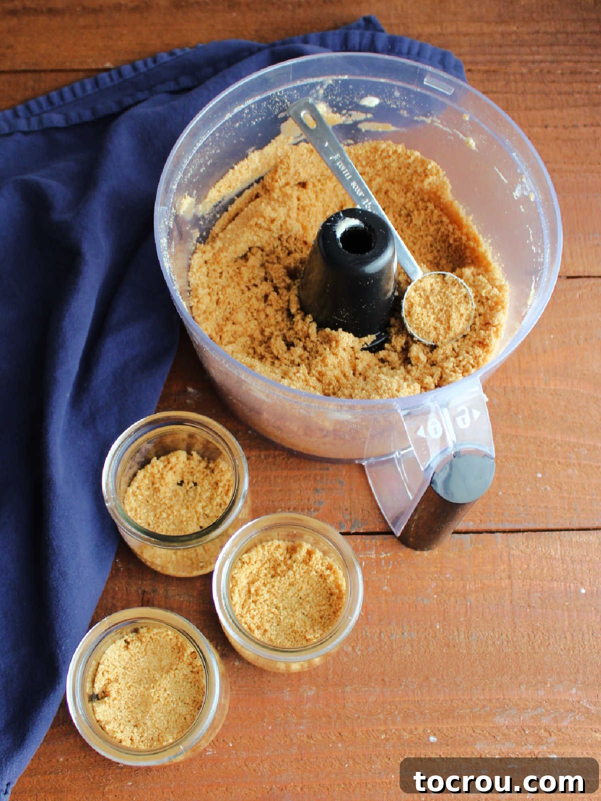 Quick Lemon Berry Jar Cheesecakes 5 Food processor with graham cracker crumb, melted butter, and sugar mixture to make crust, some scooped into small glass jars.
