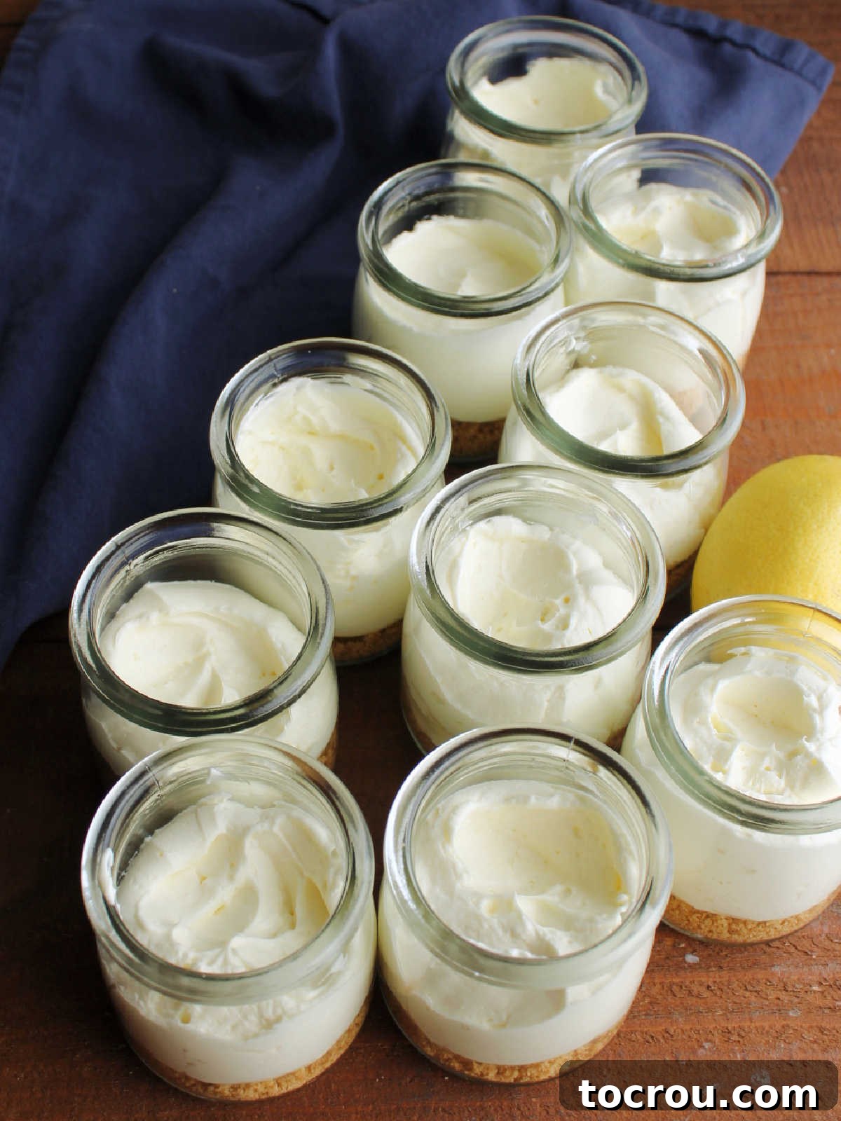 Quick Lemon Berry Jar Cheesecakes 10 Graham cracker crumbs and lemon no bake cheesecake in small glass jars, ready for blueberry sauce.