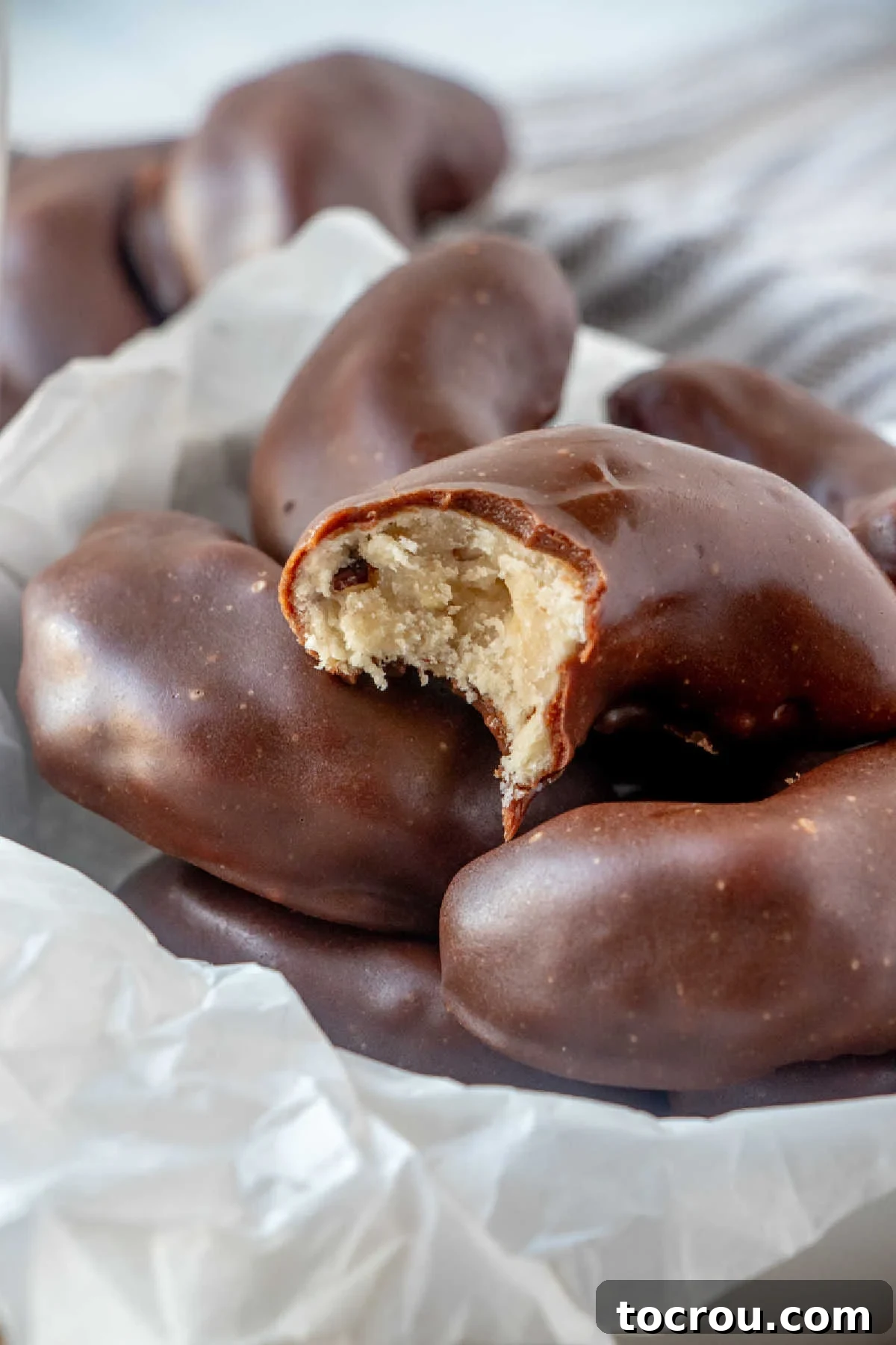 close up of bite missing out of a fudge dipped pecan crescent cookie with buttery cookie inside showing.