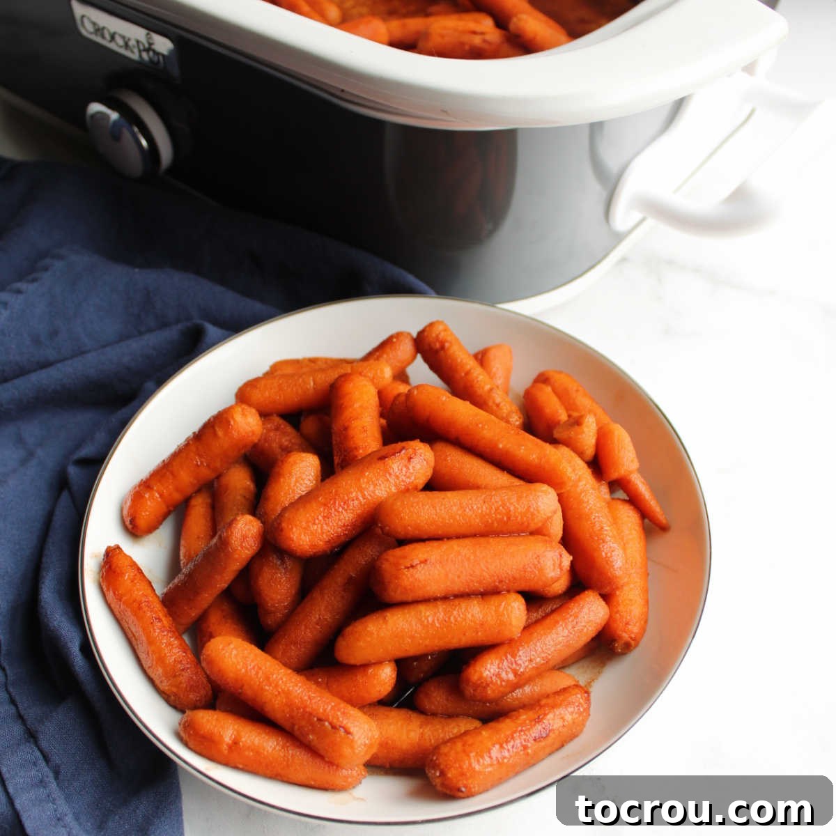 Serving bowl filled with carrots glazed in honey and cinnamon, garnished with fresh herbs.