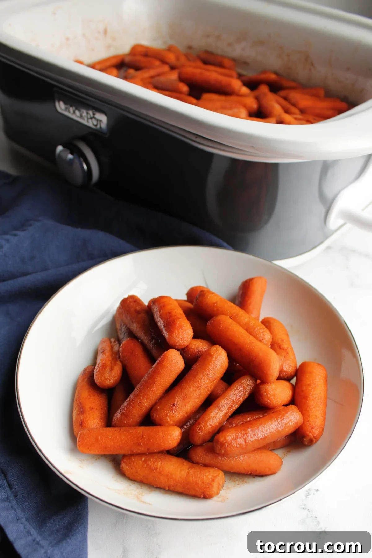 Crockpot filled with honey glazed baby carrots seasoned with cinnamon and ginger.