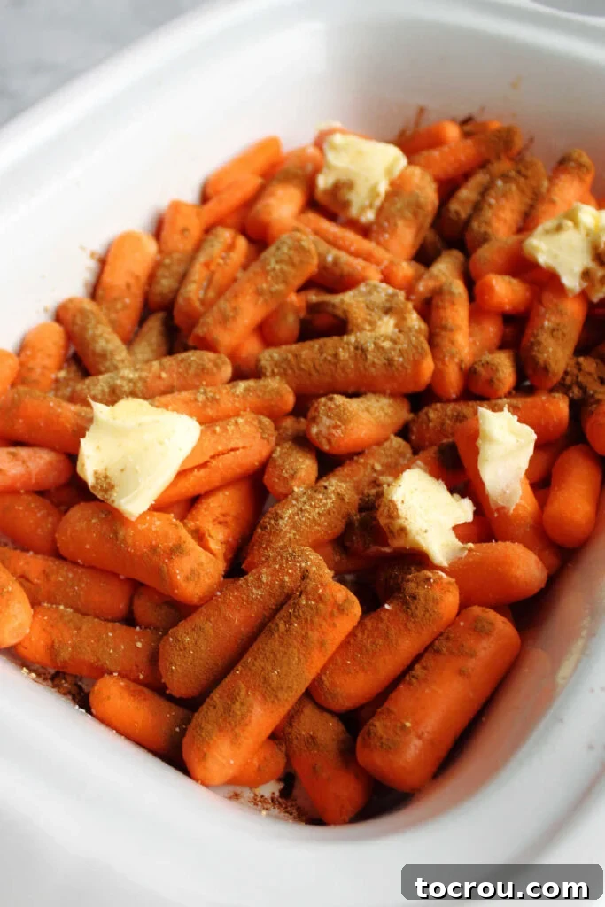 Carrots topped with cinnamon and butter in a slow cooker, before cooking.
