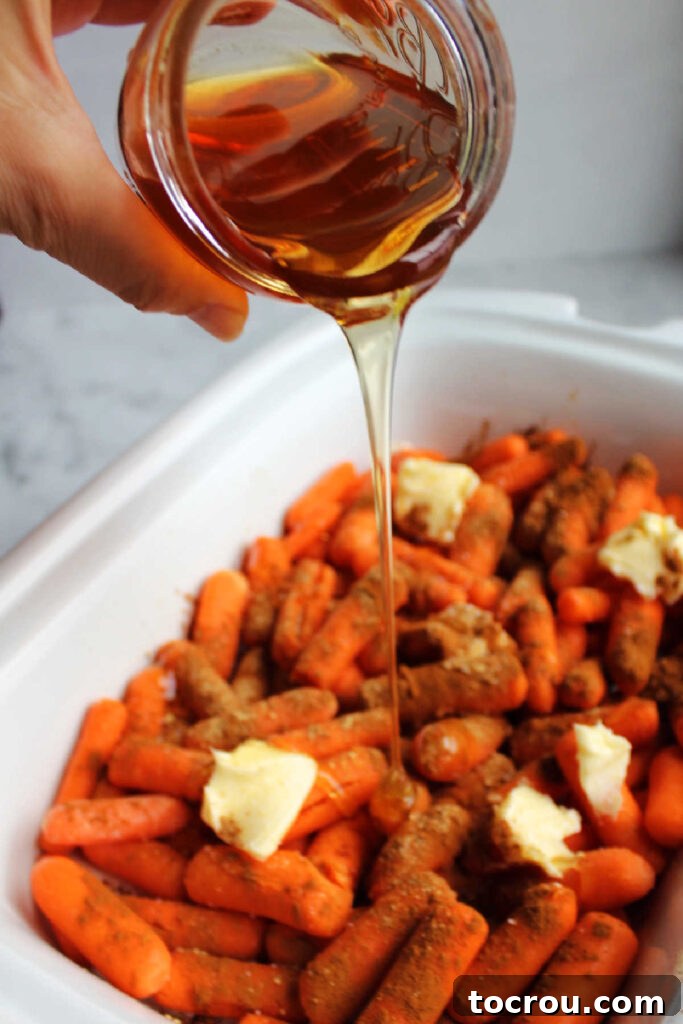 Pouring honey over carrots, butter, and cinnamon in a slow cooker.