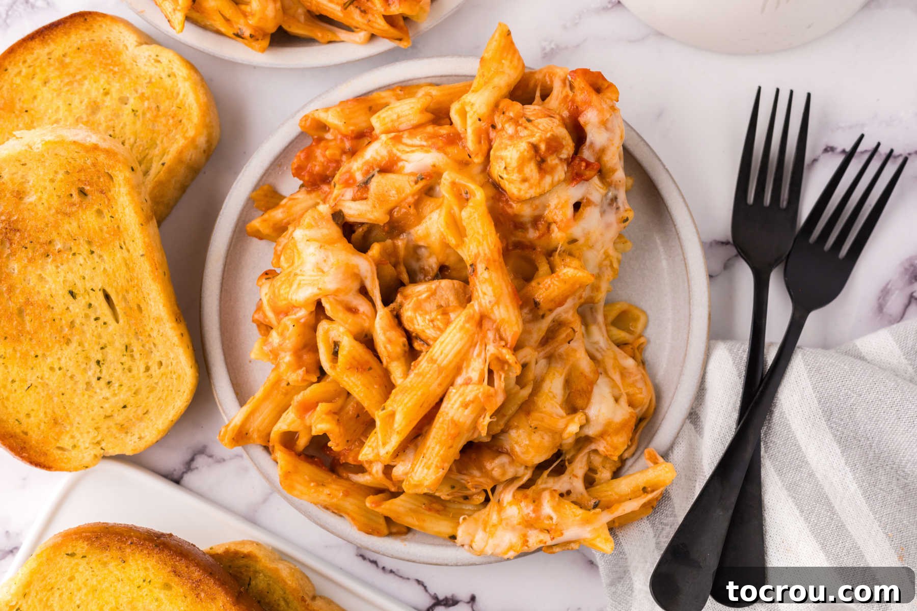 Dump-and-Bake Chicken Pasta Casserole 2 Dinner plate of chicken and penne pasta bake with cheese and garlic bread.