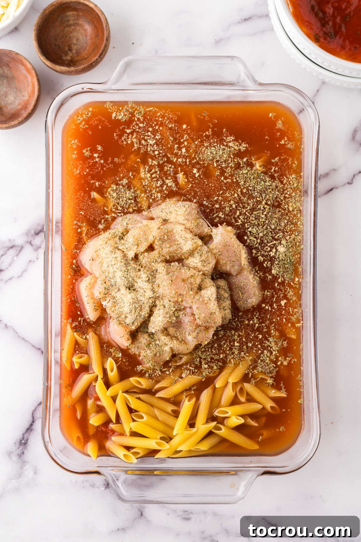 Dump-and-Bake Chicken Pasta Casserole 4 Ingredients in glass 9x13-inch baking dish, ready to be stirred together and baked.