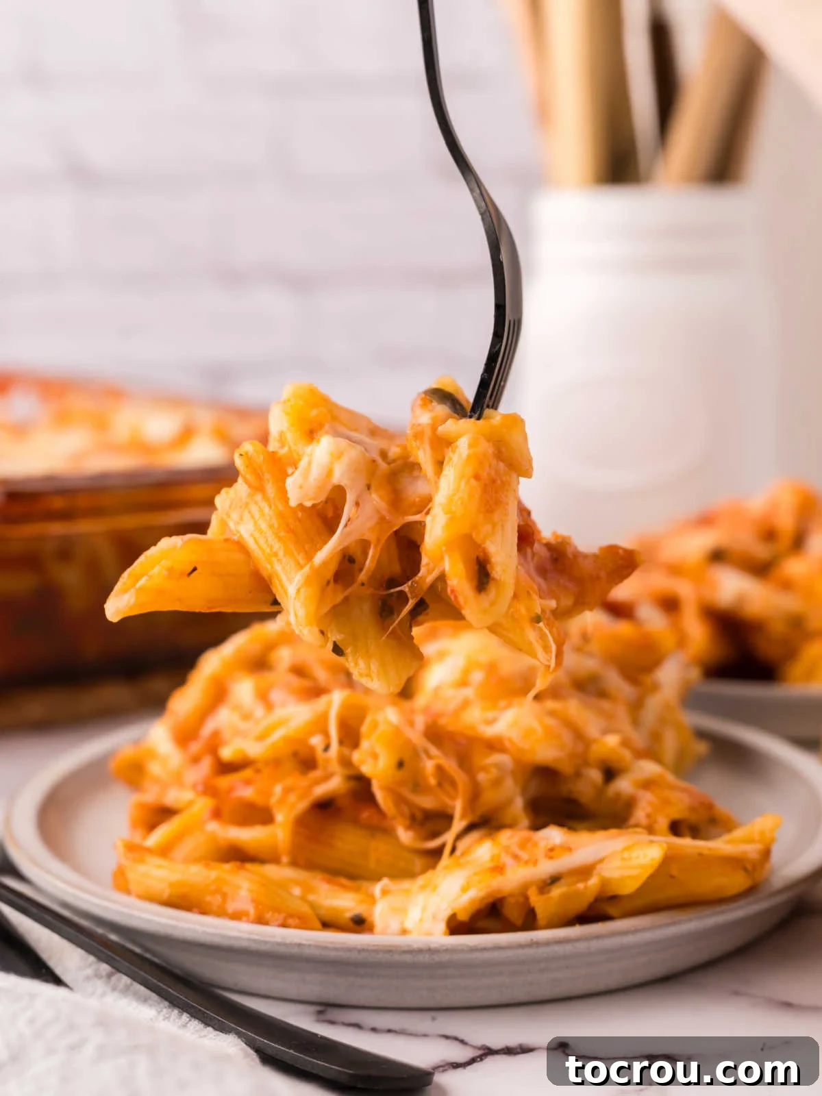 Dump-and-Bake Chicken Pasta Casserole 8 Fork getting a bite of no boil chicken pasta bake, showing tomato sauce, cooked pasta and melty cheese.