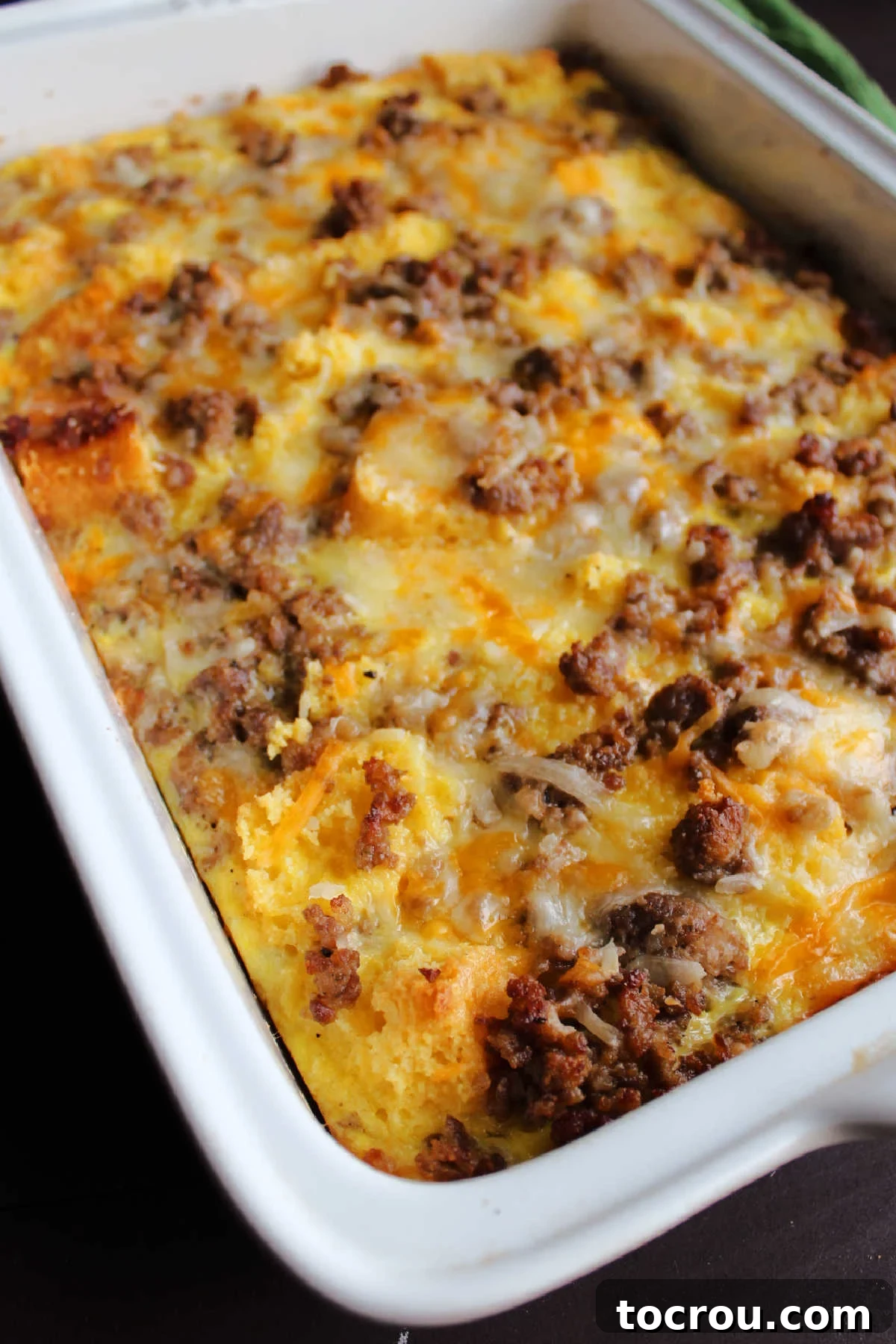 Savory Sausage Cornbread Morning Bake 4 Freshly baked egg casserole with chunks of sausage and melted cheddar cheese on top.