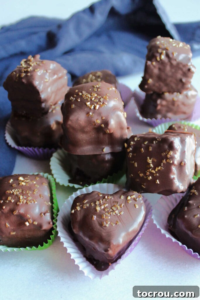 A beautifully arranged stack of chocolate-dipped chocolate petit fours, each adorned with a dusting of shimmering gold sprinkles, ready for serving.