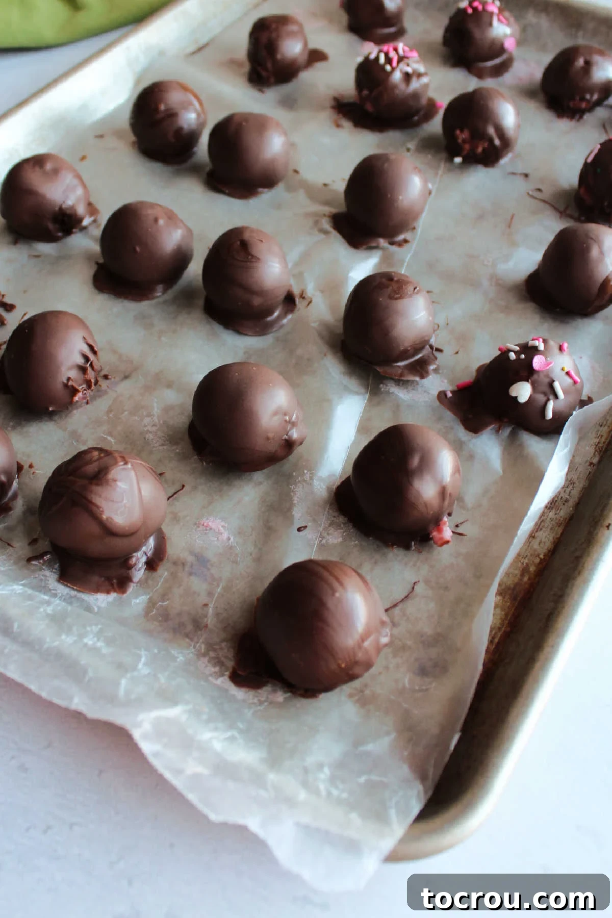 Decadent Strawberry Buttercream Truffles 5 Freshly dipped chocolate truffles arranged neatly on wax paper, allowing the chocolate coating to set beautifully.