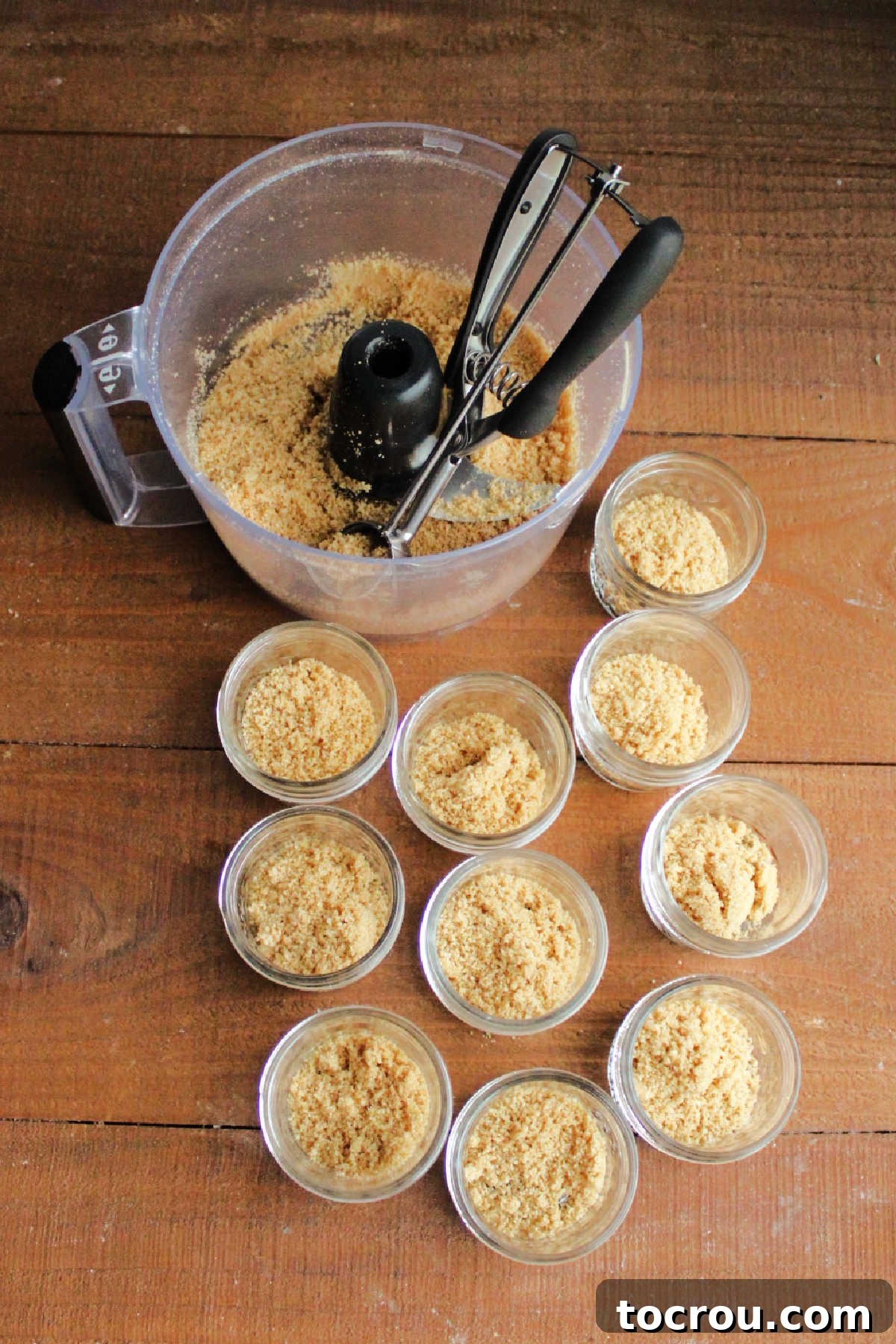 Zesty Key Lime Cheesecake Jars 5 Scooping the buttery graham cracker crumb mixture into small jars to form the base for mini cheesecakes.