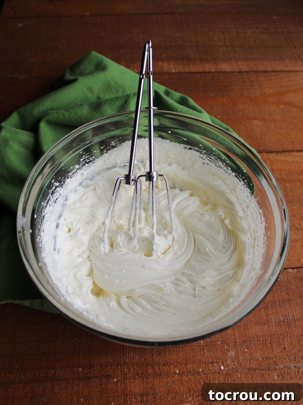 Zesty Key Lime Cheesecake Jars 8 Fluffy cream cheese whipped cream in a glass mixing bowl with electric mixer beaters, showcasing its perfect texture.
