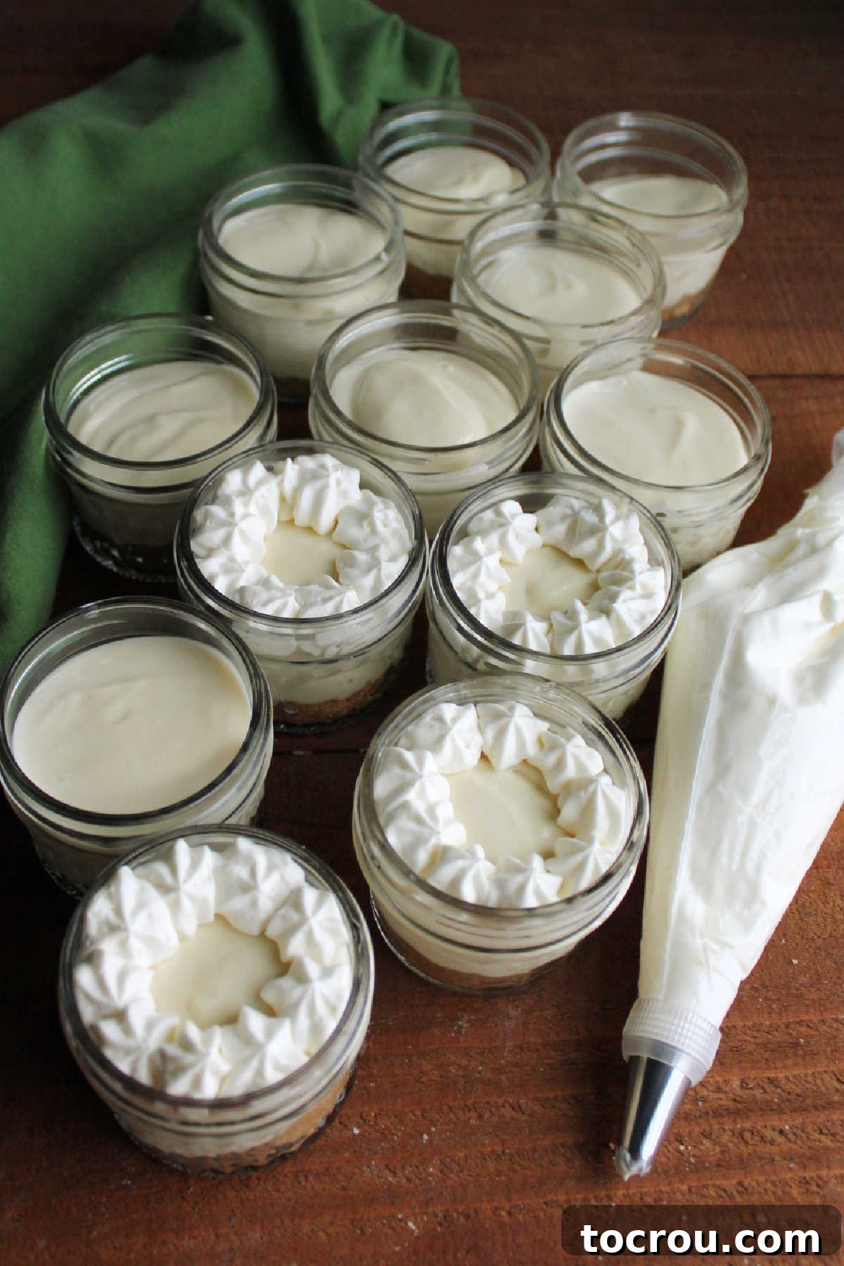 Zesty Key Lime Cheesecake Jars 9 Piping elegant cream cheese whipped cream borders onto mini no-bake key lime cheesecake jars for a decorative finish.