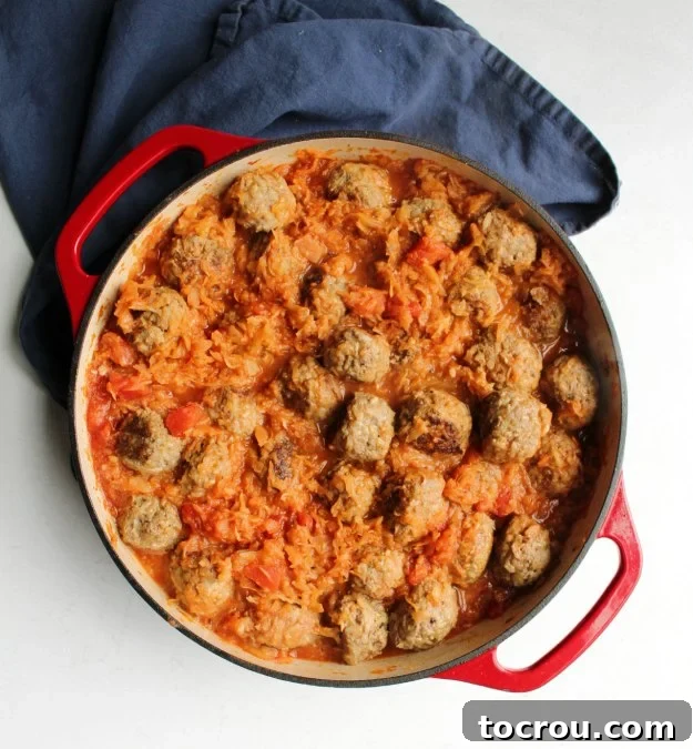 An enameled cast iron pan generously filled with perfectly cooked porcupine meatballs, nestled in their rich, homemade secret ingredient sauce, ready to be served.