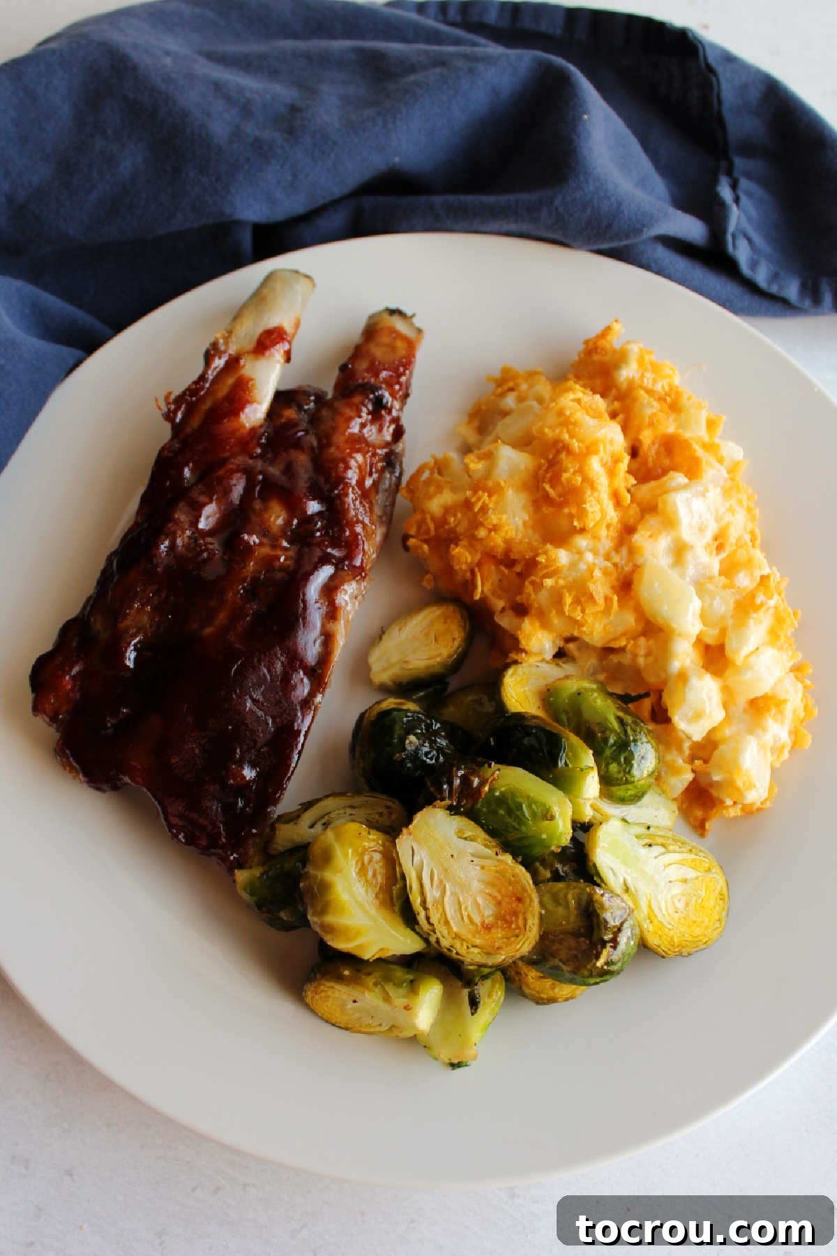 Ribs, cheesy ranch potato casserole and roasted brussels sprouts on plate. 