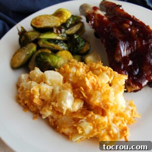Close up of cheesy ranch potatoes on dinner plate with brussels sprouts and bbq ribs.