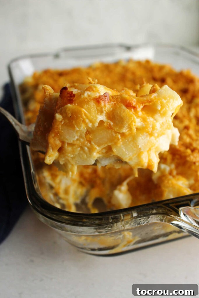 Scooping Cheesy Ranch Potatoes Lifting spoonful of cheesy ranch potatoes out of pan.