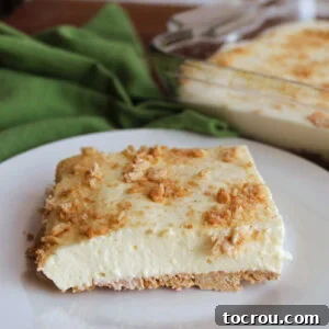 A slice of airy lemon jello no bake cheesecake with a graham cracker crust, perfectly set and ready to eat on a plate.