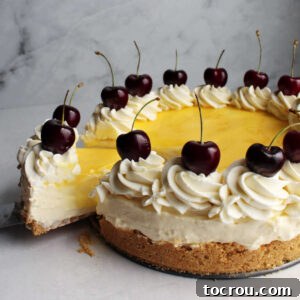 The first slice being carefully removed from a vibrant lemon no bake cheesecake, adorned with swirls of cream cheese whipped cream and bright red cherries.