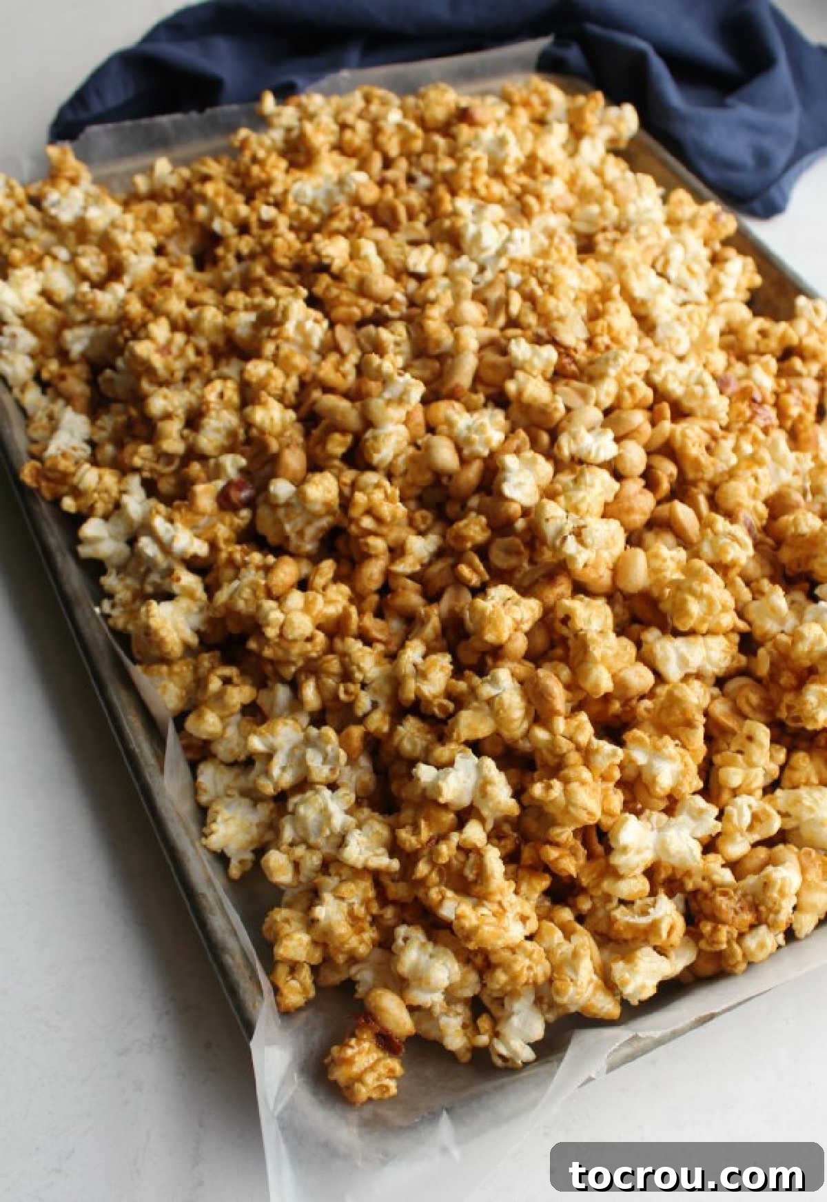 Wax paper-lined baking sheet filled with warm, cooling caramel corn.